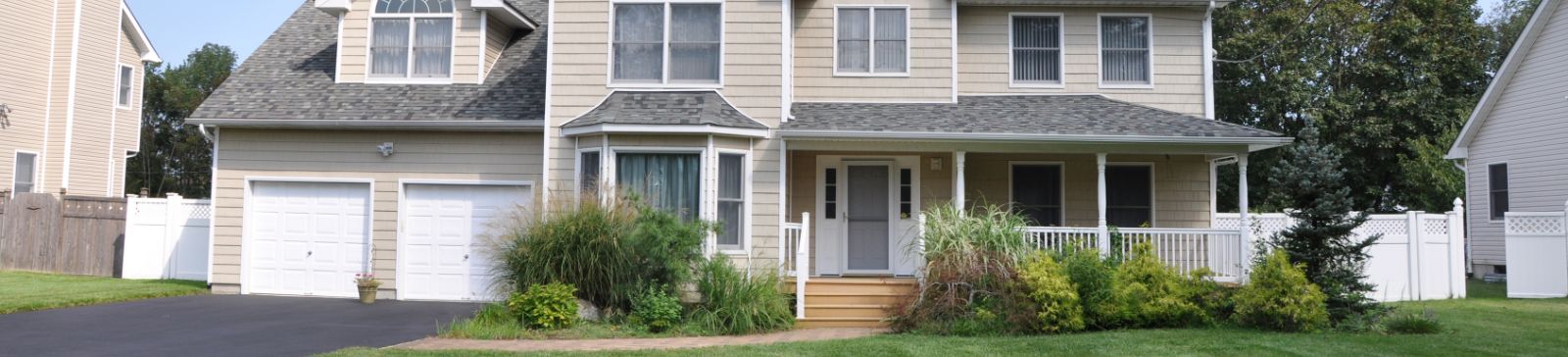 Front view of a modern suburban house with a double garage, well-kept lawn, and inviting porch, ideal for contacting our team about home services.
