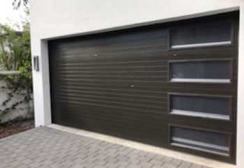 Modern dark sectional garage door with horizontal glass windows installed in Elmont NY home
