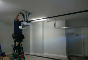 Professional garage door technician mounting an automatic opener in New Hyde Park NY home garage