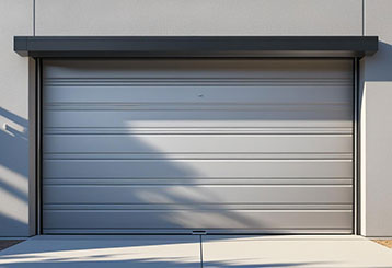 Technician servicing a silver rollup garage door on a Forest Hills, NY home for repair and maintenance.