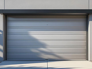 Rollup Garage Door Installation and Repair in Forest Hills, NY Technician servicing a silver rollup garage door on a Forest Hills, NY home for repair and maintenance.